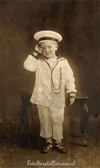 Oude foto met jongetje in matrozenpak, beschadigd en verkleurd – origineel beeld vóór fotorestauratie.